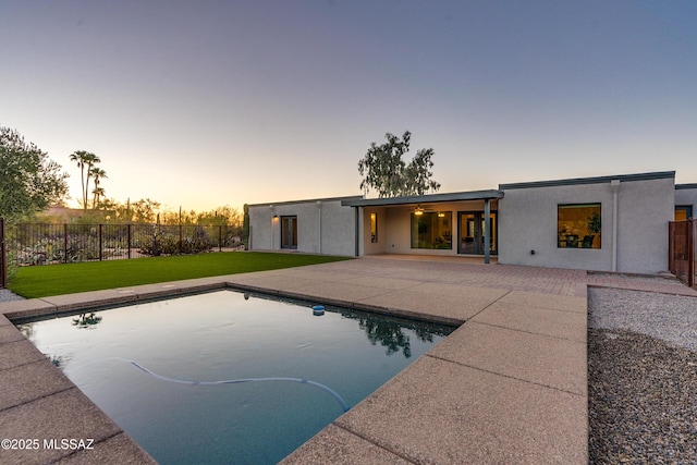 pool at dusk with a yard and a patio