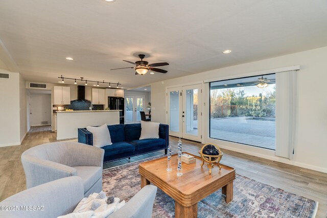 living room with french doors, ceiling fan, and light hardwood / wood-style floors