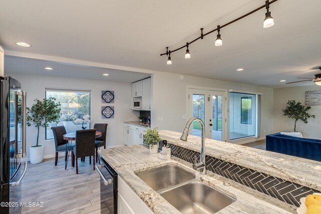 kitchen with white cabinetry, backsplash, range hood, and light stone countertops