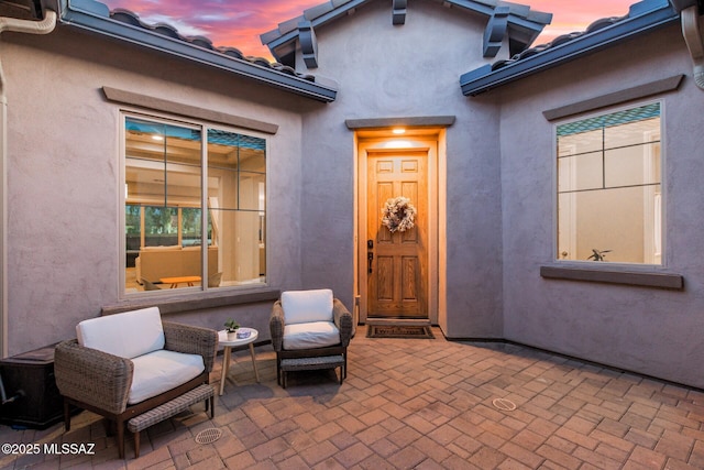 exterior entry at dusk featuring a patio