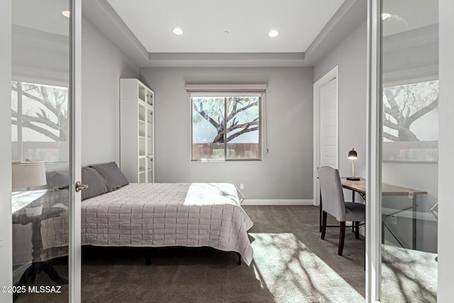 bedroom featuring a tray ceiling and dark colored carpet