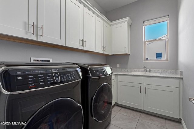 clothes washing area featuring cabinets, sink, washing machine and dryer, and light tile patterned floors