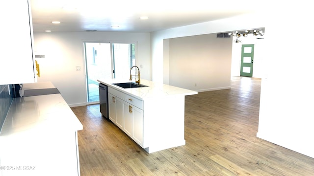 kitchen with sink, white cabinets, light stone counters, stainless steel dishwasher, and a center island with sink