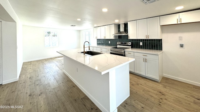 kitchen with white cabinetry, stainless steel electric range, wall chimney range hood, and sink