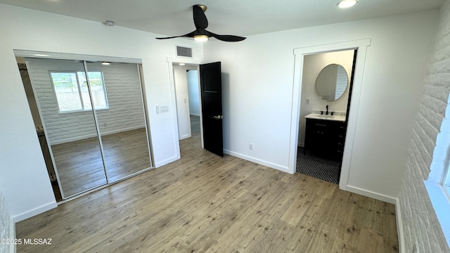 unfurnished bedroom with ensuite bathroom, light hardwood / wood-style floors, a closet, ceiling fan, and sink