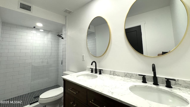 bathroom with toilet, a tile shower, and vanity