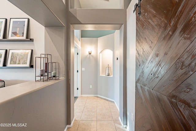 corridor with a barn door and light tile patterned floors