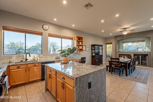 kitchen featuring light tile patterned flooring, wine cooler, light stone counters, black dishwasher, and a kitchen island