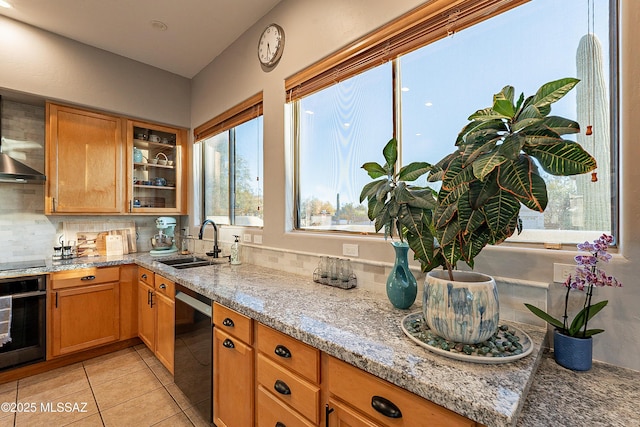 kitchen featuring tasteful backsplash, sink, light tile patterned floors, black appliances, and light stone countertops