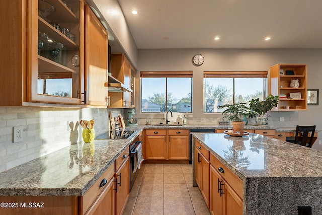 kitchen featuring a kitchen island, sink, backsplash, light stone countertops, and black electric cooktop