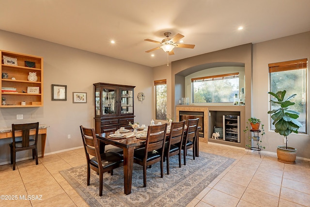 tiled dining space featuring a tile fireplace, wine cooler, and ceiling fan