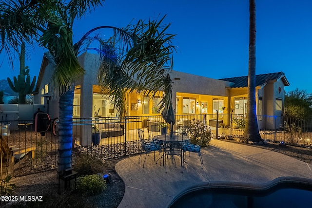 rear view of property featuring a fenced in pool and a patio area