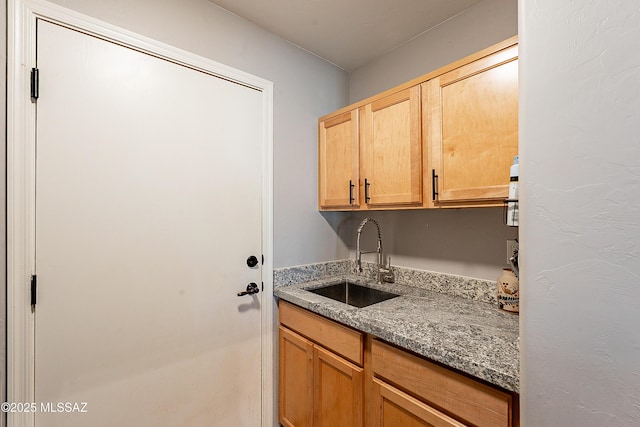 kitchen featuring stone countertops, sink, and light brown cabinetry