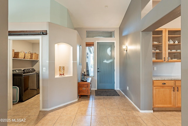 tiled entrance foyer with lofted ceiling and washing machine and clothes dryer