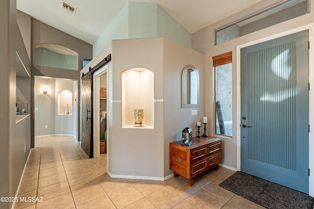 tiled foyer entrance featuring vaulted ceiling and a barn door