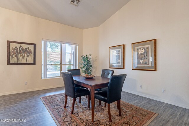 dining room with high vaulted ceiling, dark wood-type flooring, and a notable chandelier