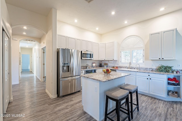 kitchen featuring a kitchen island, sink, white cabinetry, light stone countertops, and appliances with stainless steel finishes