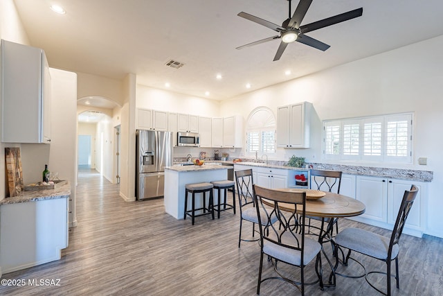 dining room featuring ceiling fan, sink, and light hardwood / wood-style flooring