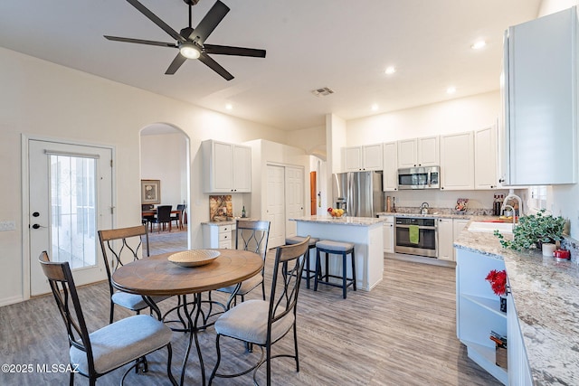 dining room featuring ceiling fan, sink, and light hardwood / wood-style flooring