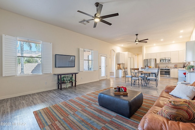 living room with ceiling fan, a healthy amount of sunlight, and light wood-type flooring