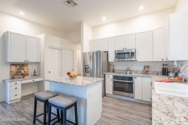 kitchen with sink, a breakfast bar, appliances with stainless steel finishes, a center island, and white cabinets