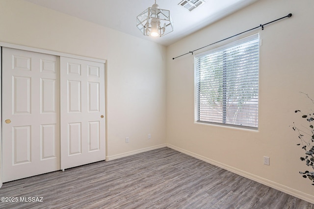 unfurnished bedroom featuring light wood-type flooring, a closet, and a notable chandelier