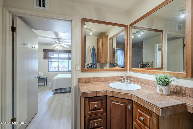 ensuite bathroom featuring visible vents, ensuite bath, ceiling fan, wood finished floors, and vanity