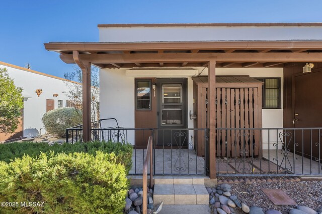 property entrance with a gate, fence, and a porch