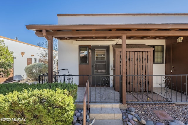 doorway to property featuring fence and stucco siding