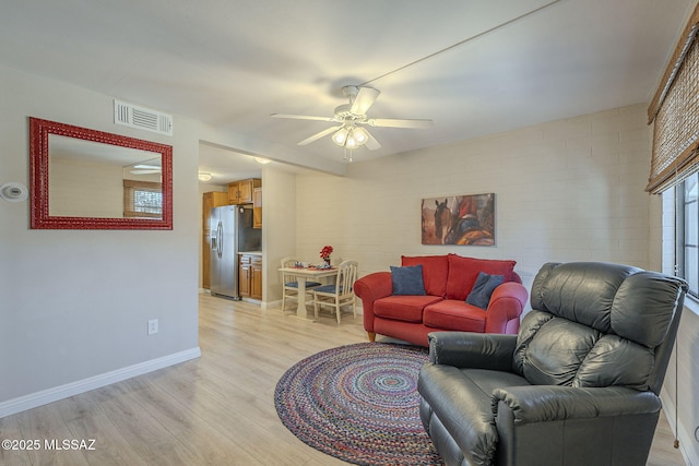 living room with light wood-style floors, baseboards, visible vents, and ceiling fan