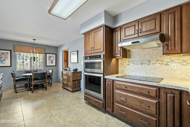 kitchen with a chandelier, hanging light fixtures, light stone countertops, double oven, and black electric cooktop