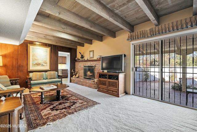 living room featuring wood walls, wood ceiling, carpet floors, a fireplace, and beamed ceiling