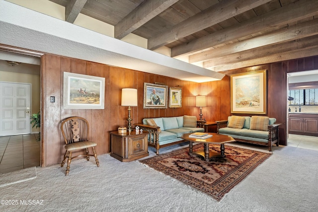 carpeted living room featuring beam ceiling, wooden walls, and wood ceiling