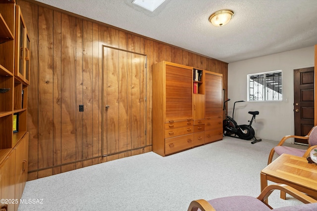 sitting room featuring wood walls, a textured ceiling, and carpet floors