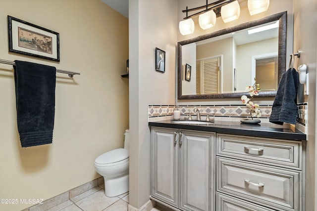 bathroom with toilet, vanity, tile patterned floors, and backsplash