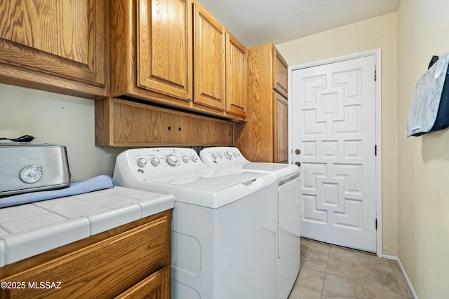 laundry room featuring light tile patterned flooring, separate washer and dryer, and cabinets