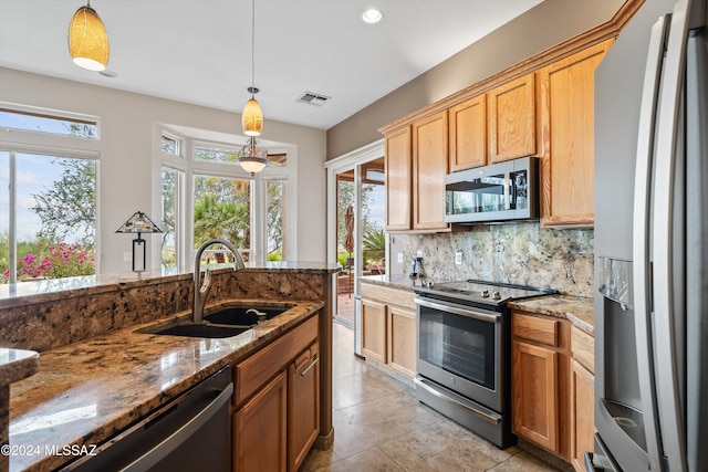 kitchen with stainless steel appliances, sink, tasteful backsplash, and decorative light fixtures