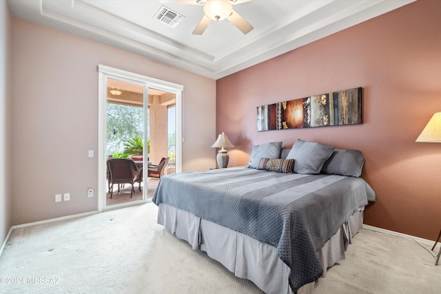 bedroom with ceiling fan, access to exterior, light carpet, and a raised ceiling