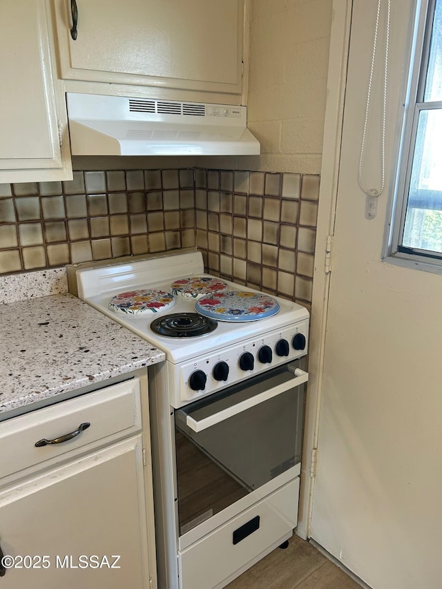 kitchen with light hardwood / wood-style floors, light stone countertops, white range with electric stovetop, white cabinetry, and tasteful backsplash