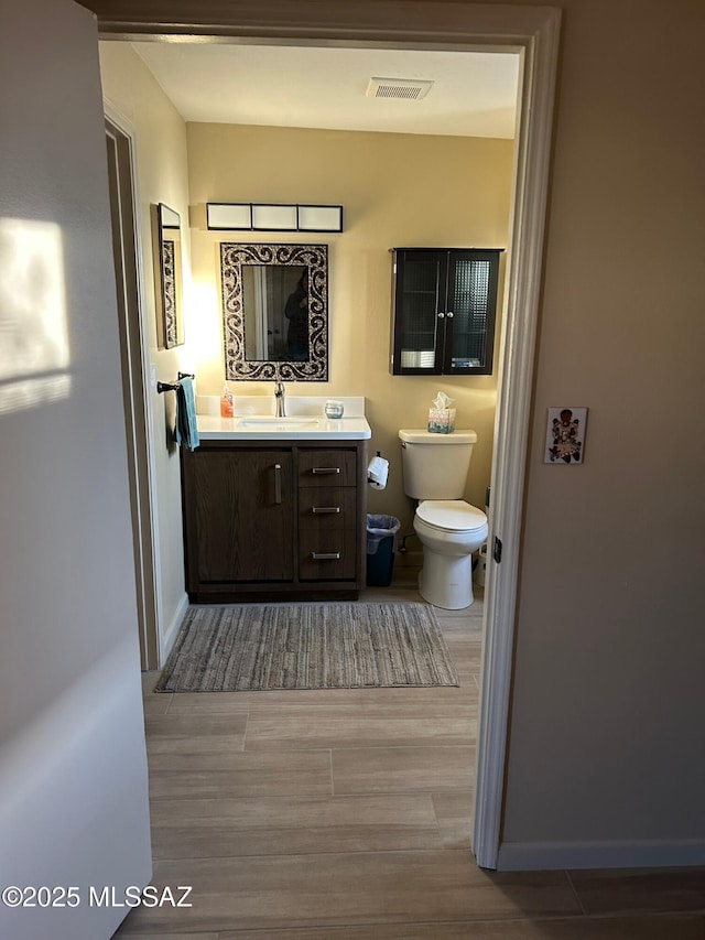 bathroom with hardwood / wood-style flooring, vanity, and toilet