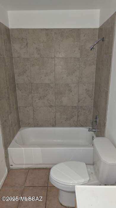 bathroom featuring tile patterned flooring, tiled shower / bath combo, and toilet