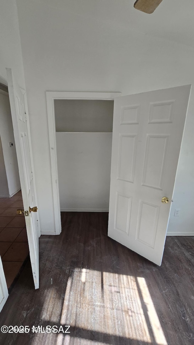 unfurnished bedroom featuring a closet and dark wood-type flooring