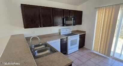 kitchen featuring sink, light tile patterned floors, dark brown cabinets, and white electric stove