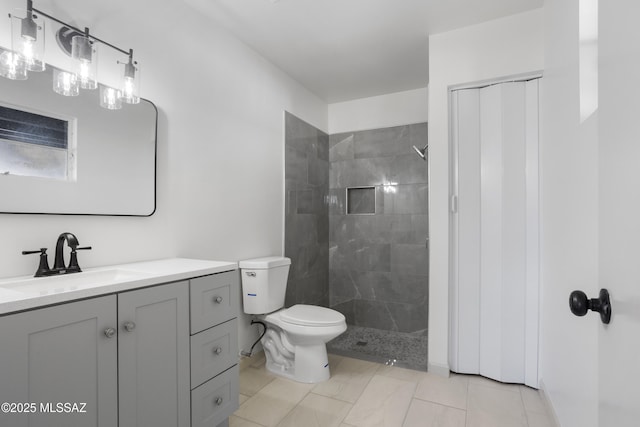 bathroom featuring toilet, a tile shower, and vanity