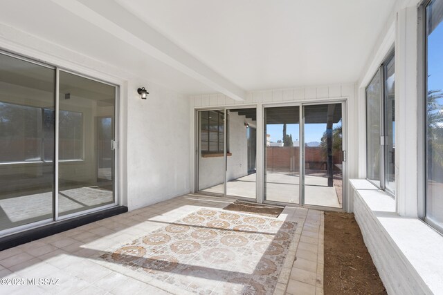 unfurnished sunroom with beam ceiling