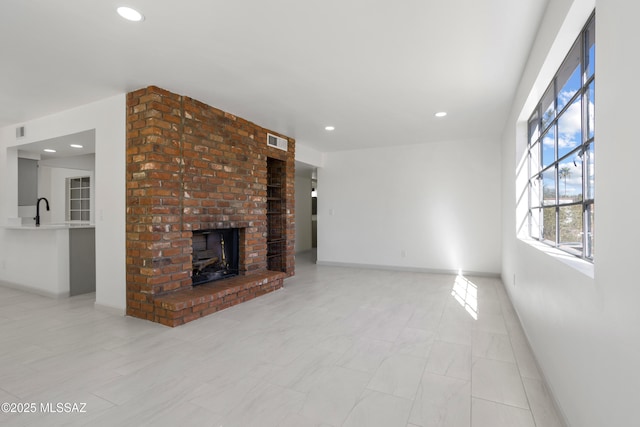 unfurnished living room with sink and a brick fireplace