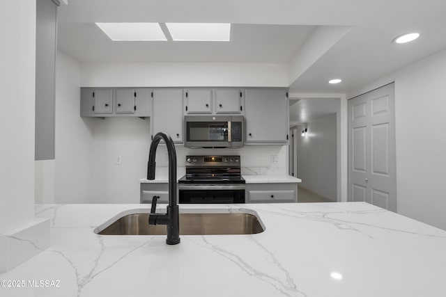 kitchen with light stone countertops, sink, black range with electric cooktop, and gray cabinets