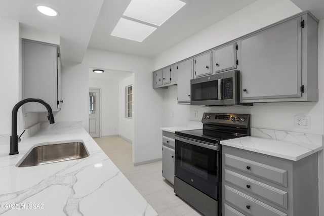 kitchen featuring sink, electric stove, light stone counters, and gray cabinetry