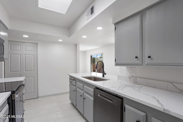 kitchen with light stone countertops, dishwasher, gray cabinetry, and sink