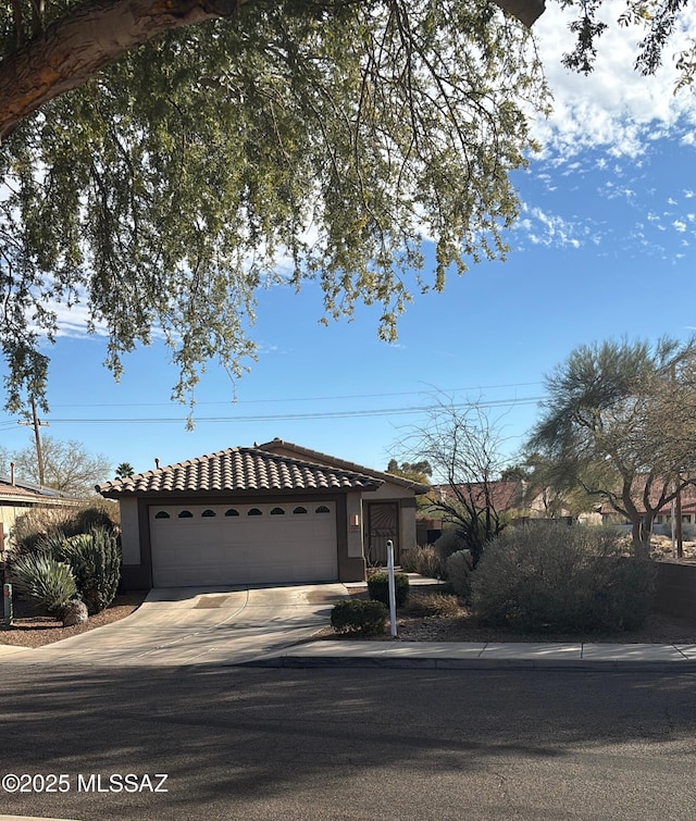 view of front of home with driveway, an attached garage, a tile roof, and stucco siding